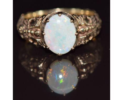 A 9ct gold ring set with an opal, with embossed decoration to the shoulders, 5.1g, size O