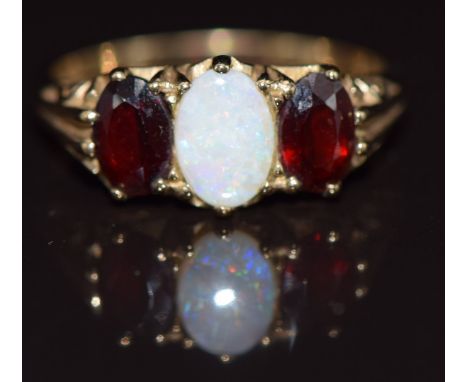 A 9ct gold ring set with an opal and two garnets, 2.6g, size M