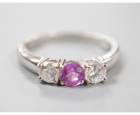 A modern platinum, pink sapphire and two stone round cut diamond set ring, size O, gross weight 5.4 grams, the sapphire weigh