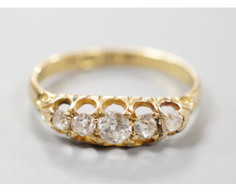 A late Victorian 18ct gold and graduated claw set five stone diamond half hoop ring, size N, gross weight 2.5 grams.