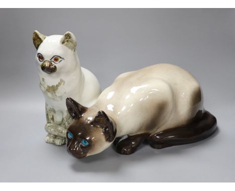 A Kensington ceramic lurking Siamese cat with blue glass eyes by Winstanley, together with another, tallest 26cm