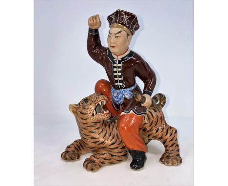 A Chinese ceramic figure of man seated on a tiger holding its tail, unmarked, height 21.5cm(In good condition)