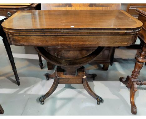 A Regency period crossbanded rosewood card table with rounded rectangular fold-over top, baize lined with boxwood line inlay,