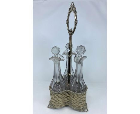 A 19th century decanter in pierced and cast silver plate, central ring handle, with 3 slice cut decanters 