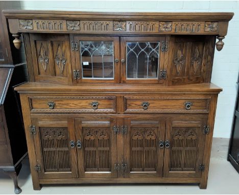 A reproduction oak large buffet/sideboard, heavily carved, with glazed cupboard over 2 drawers and double cupboards 