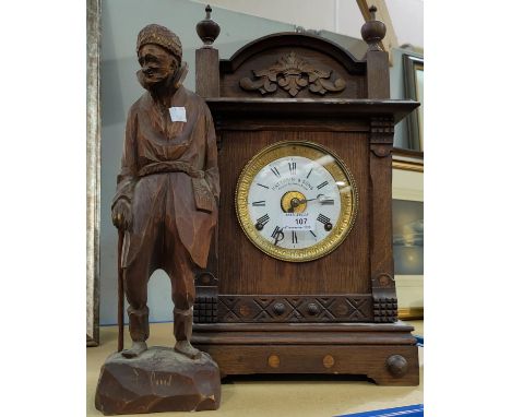An Edwardian mantel clock in architectural oak case by Fattorini &amp; Sons, Bradford; a carved wooden figure of an old man; 