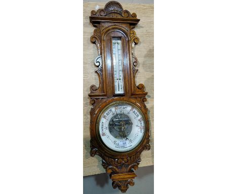 An Edwardian aneroid barometer with exposed mechanism, and thermometer, in carved golden oak case, by John C Chapman, York 