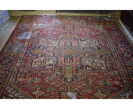 A Persian carpet, with geometric motifs on a red ground, within a multi border, 364 x 261 cm