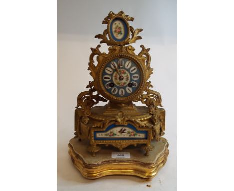 A late Victorian mantel clock, the 7.5 cm porcelain dial with Roman numerals, fitted an eight day movement, in a gilt brass a