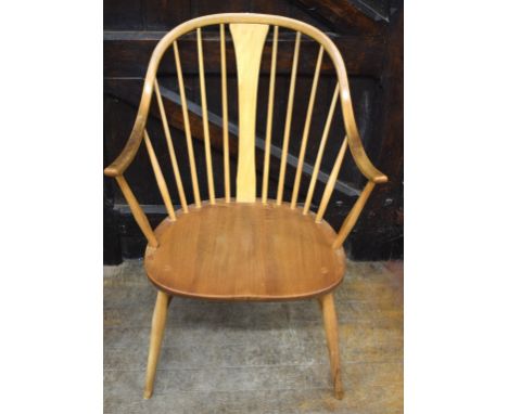 A pair of Ercol beech and elm comb back armchairs, an Ercol beech and elm drop leaf dining table, 122 cm wide, a matching pai