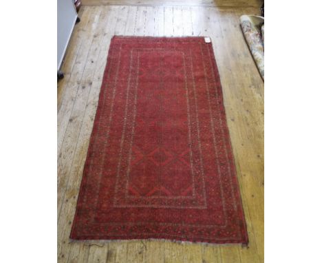 An eastern style carpet, with geometric motifs on a red ground, 112  x 206 cm
