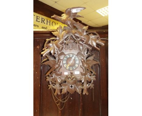 A cuckoo wall clock, the 13.5 cm diameter dial with Roman numerals, in a wooden case, carved birds, flowers and foliage, 51 c