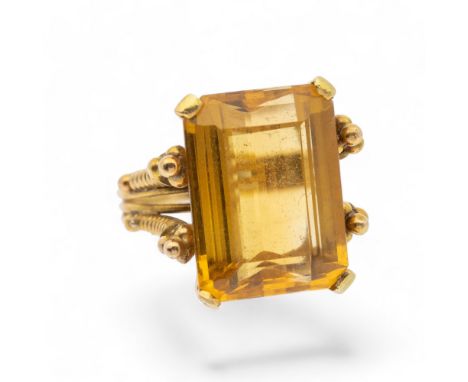 A citrine and yellow metal dress ring, set with a rectangular stone approx 17 x 12mm, claw set with beaded decoration, size K