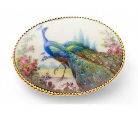 An oval ceramic brooch, painted with a peacock decoration, within a yellow metal mount with rope border, length approx 58mm, 