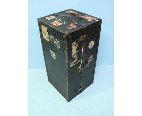 A black steamer trunk, opening to reveal a fitted interior with drawers and hanging space for clothes. 110cm.