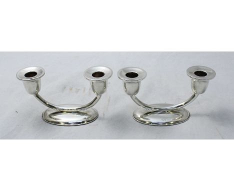 A pair of .900 grade silver two light candelabra, raised on oval bases.