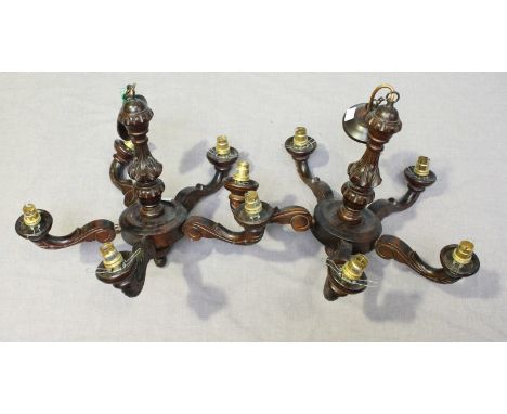 A pair of stained-wood five-light electroliers with frosted glass shades.