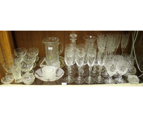 A shelf of assorted mixed glassware including a quantity of wine glasses and other drinking glass, a decanter and a vase etc.