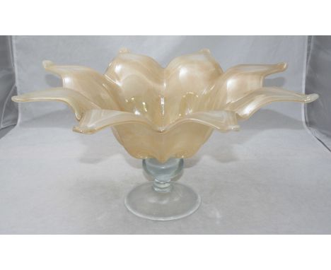 A light orange/beige glass centrepiece modelled as an open flower, raised on a turned, clear glass stem to splayed foot-rim. 
