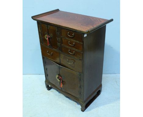 A 20th century Korean hardwood cabinet, comprising of multiple cupboards and drawers, to a shaped apron and raised on shaped 