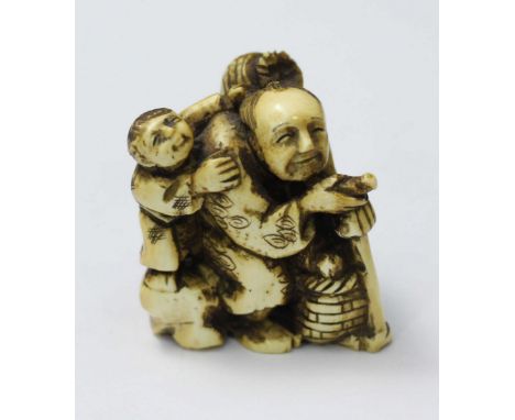 A Japanese Meiji Period Carved and stained Ivory Netsuke figure of an elderly man with a staff, wicker baskets, and a child o