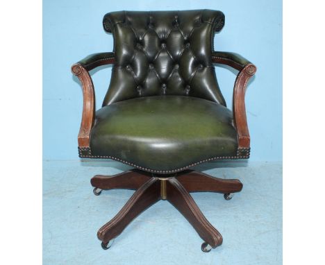 A green leather upholstered Captain's chair with button back on swivel base, together with a circular coffee table with repla