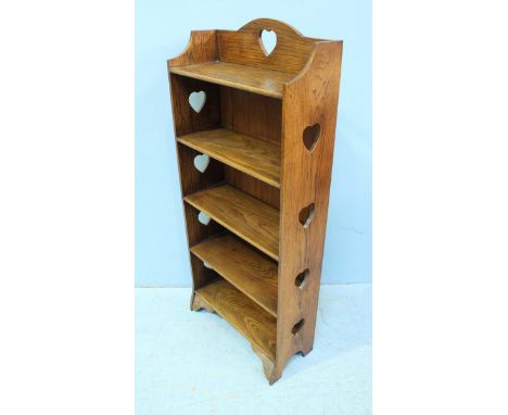 An Arts & Crafts oak bookcase with five closed back shelves, decorated to the sides and top with pierced love heart motifs an