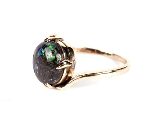 A black boulder opal ring, the cabochon 9.5 x 9.0mm, on 9ct yellow gold crossover mount and shank, ring size N, 2.5g gross.