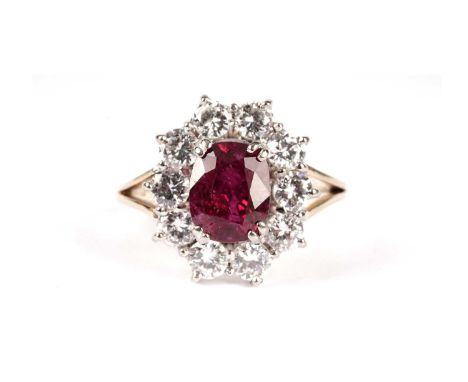 A ruby and diamond cluster ring, the oval facet-cut ruby measuring 7.5 x 5.7 x 4.5mm, surrounded by ten brilliant-cut diamond