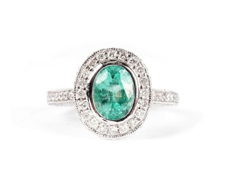 An emerald and diamond cluster ring, the oval facet-cut emerald weighing approximately 0.91 carats, surrounded by brilliant-c