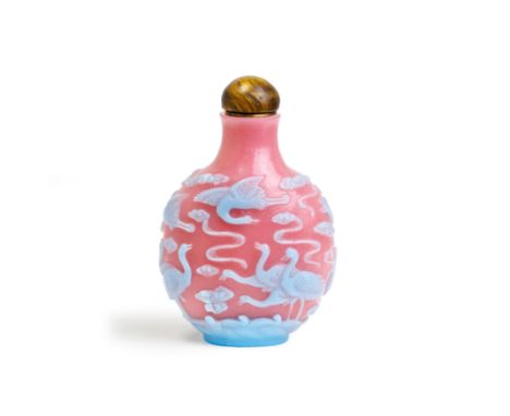 A Chinese turquoise-blue overlay pink glass 'cranes' snuff bottle20th centuryFinely carved throughout with twelve cranes amon