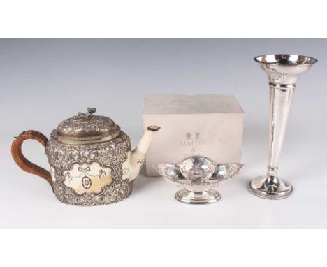 A George V silver mounted Royal Worcester porcelain teapot of oval form, the embossed domed hinged lid with flower finial abo