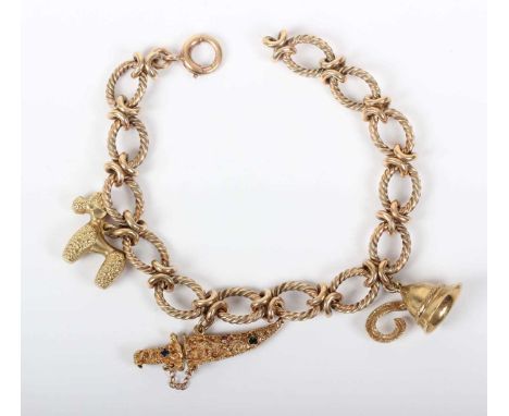 A 9ct gold bracelet in a ropetwist oval and entwined link design, on a boltring clasp, fitted with three charms, comprising a
