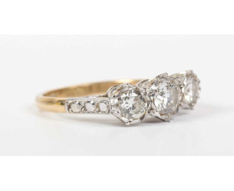 A gold and diamond three stone ring, mounted with circular cut diamonds, detailed ‘18ct’, weight 3.2g, total diamond weight a