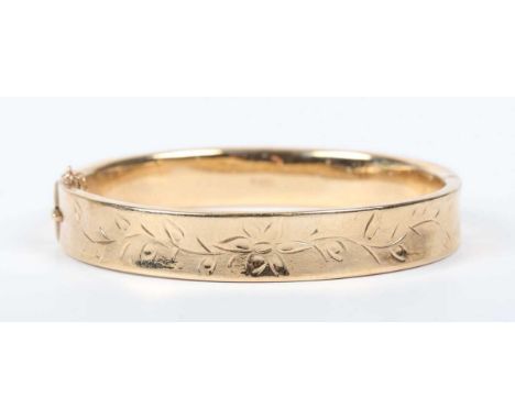 A 9ct gold oval hinged bangle with floral engraved decoration, on a snap clasp, Birmingham 1968, weight 14.5g, inside width 5