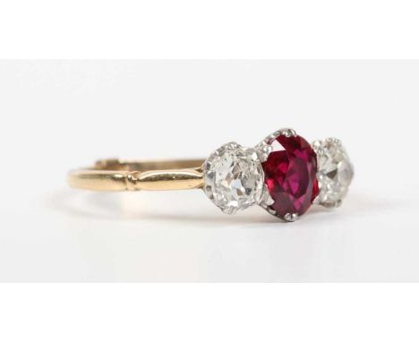 A gold, ruby and diamond ring, claw set with the oval cut ruby between two old cut cushion shaped diamonds, unmarked, fitted 