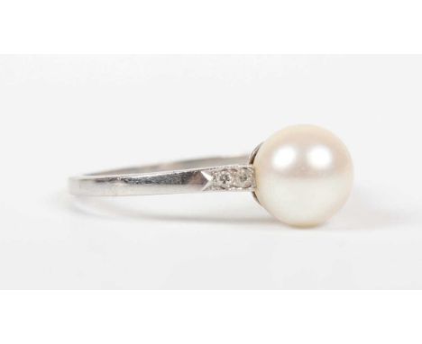 A white metal, pearl and diamond ring, mounted with a pearl between diamond set shoulders, unmarked, weight 2.6g, ring size a