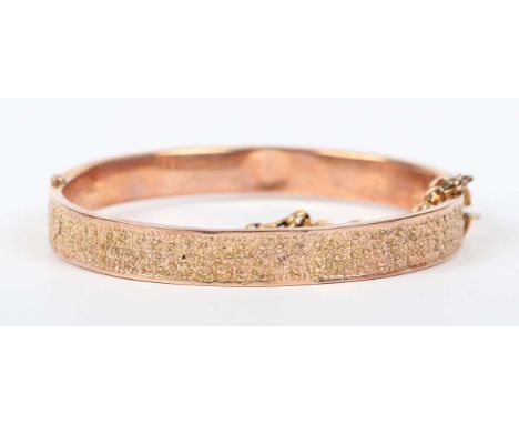 A 9ct gold circular hinged bangle, the front with a textured finish, Birmingham 1917, weight 9.6g, inside width 5.5cm.