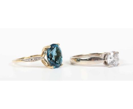 A gold ring, claw set with an oval cut treated blue topaz between diamond three stone shoulders, detailed ‘WKRUK’, otherwise 