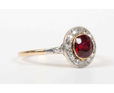 A gold, ruby and diamond cluster ring, mounted with the cushion shaped ruby within a surround of old cut diamonds between dia