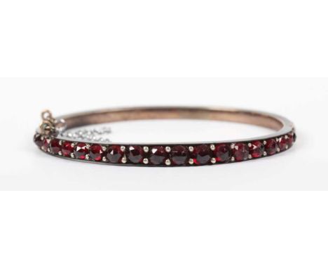A Bohemian garnet oval hinged bangle on a snap clasp, unmarked, inside width 5.3cm.