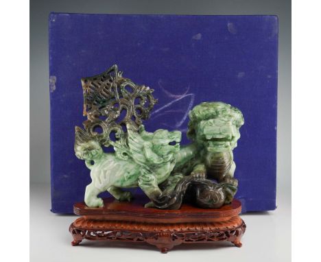 A Chinese jade carving featuring a pair of intricately detailed guardian lions, one larger and one smaller, both rendered in 