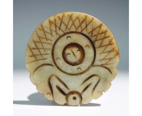 A circular carved jade ornament featuring finely incised geometric and abstract motifs. The central design is framed by a rin