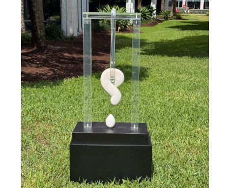 A striking modernist sculpture featuring a carved marble question mark suspended within a clear Lucite frame, creating a comp