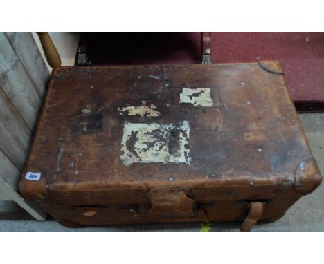 An old leather travelling trunk by Finnigans Ltd of Manchester and Liverpool containing a quantity of textiles including dama