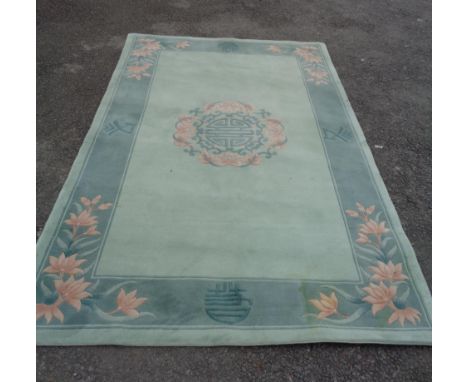 A large modern Chinese washed wool rug with central floral medallion and floral sprays on dark green border and light green g