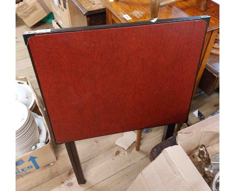 A vintage card table with red leather inset top, set on a folding painted wooden base