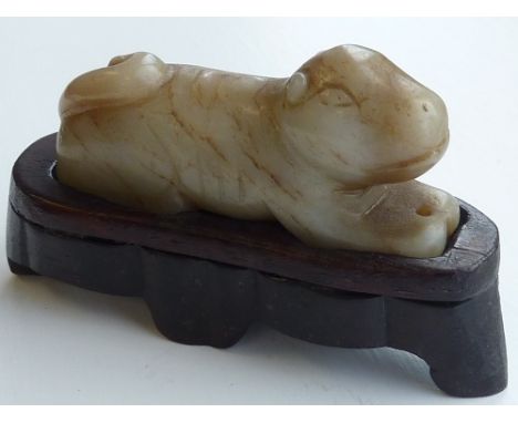 A Chinese carved Celadon Jade of a recumbent Beast, the two front legs pierced with a hole for suspension, the Celadon colour