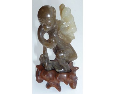 A Chinese Jade Carving of a monkey and Cubs, one upon its back and the other at its feet, the Celadon stone of a mottled dark