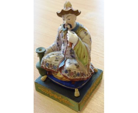 A 19th century Continental hand-decorated porcelain Figure of a Chinaman seated upon a gilt tasseled cushion, in his right ha